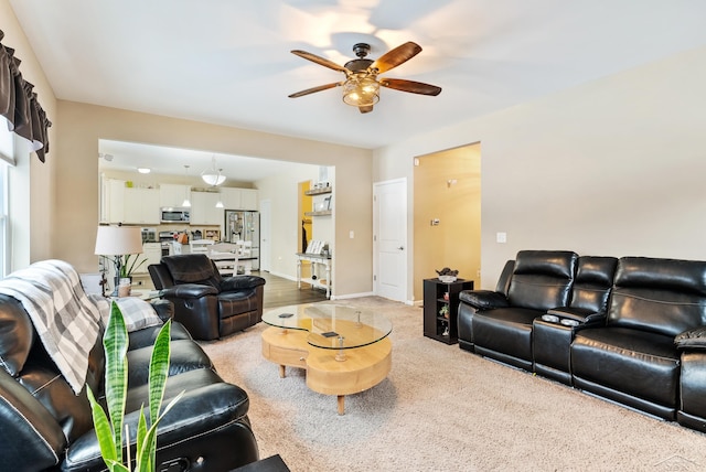 living room featuring baseboards, a ceiling fan, and light colored carpet