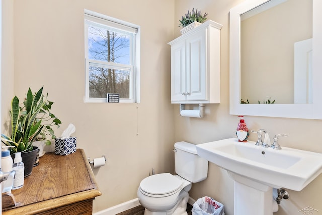 half bathroom featuring a sink, baseboards, and toilet