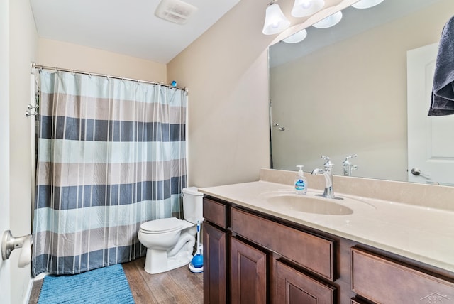 bathroom featuring vanity, toilet, a shower with shower curtain, wood finished floors, and visible vents