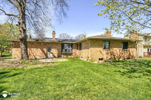 rear view of house featuring brick siding, a yard, and a chimney