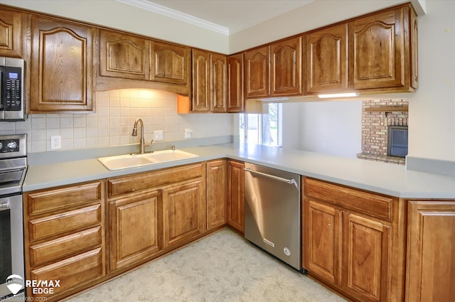 kitchen featuring a peninsula, appliances with stainless steel finishes, brown cabinetry, and a sink