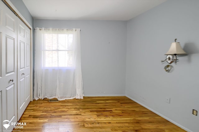 unfurnished bedroom with baseboards, wood finished floors, and a closet