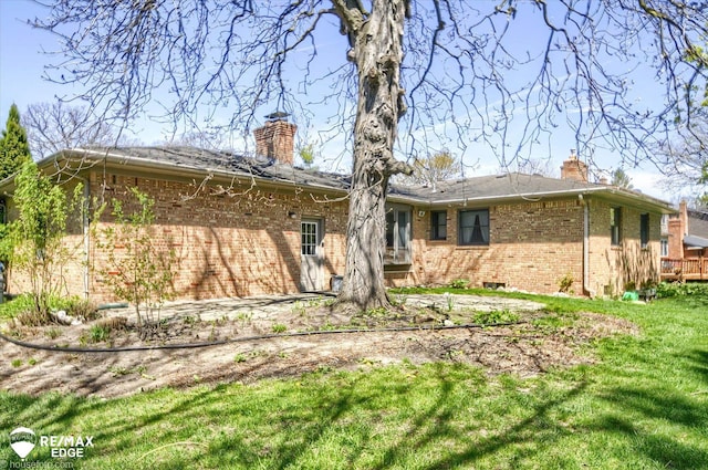 back of property with a yard, brick siding, and a chimney