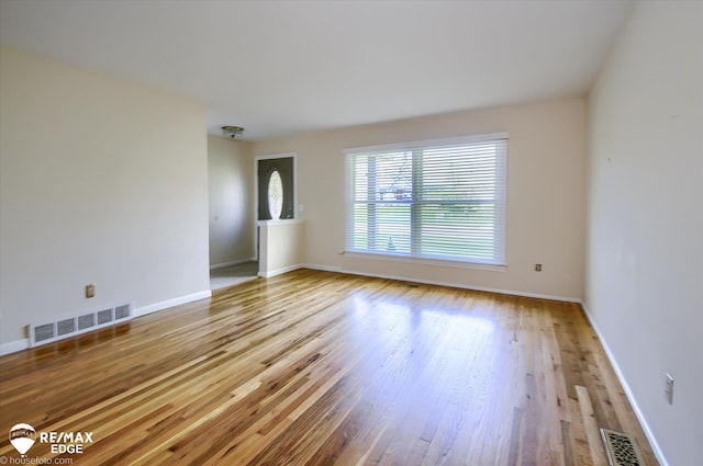 empty room with baseboards, wood finished floors, and visible vents