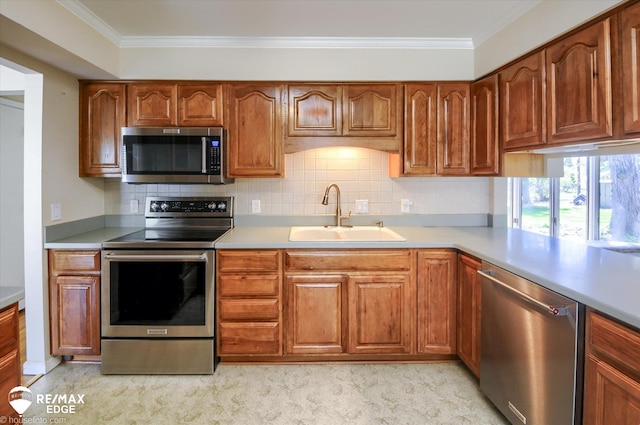 kitchen with crown molding, appliances with stainless steel finishes, a sink, light countertops, and decorative backsplash