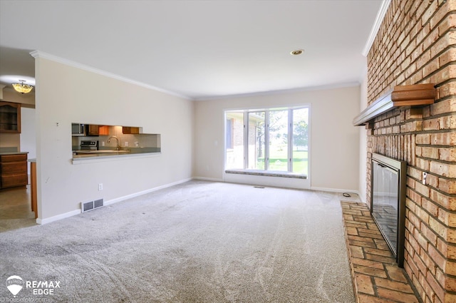 unfurnished living room featuring visible vents, ornamental molding, baseboards, and a brick fireplace
