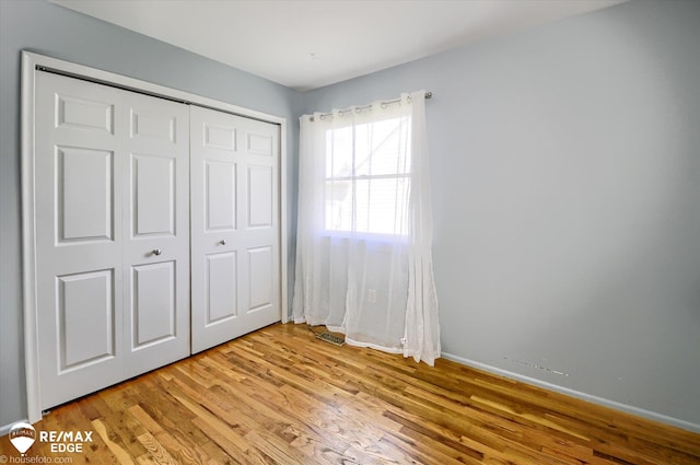 unfurnished bedroom featuring a closet, light wood-style flooring, and baseboards