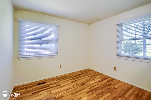 unfurnished room with a healthy amount of sunlight, baseboards, light wood-style flooring, and visible vents