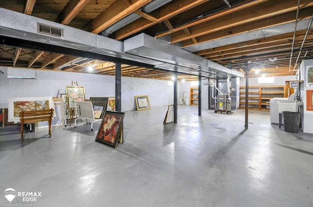 below grade area with concrete block wall, washer / dryer, heating unit, and visible vents