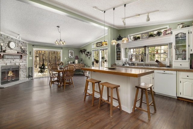 kitchen with a kitchen breakfast bar, dark wood-style floors, a textured ceiling, dishwasher, and vaulted ceiling