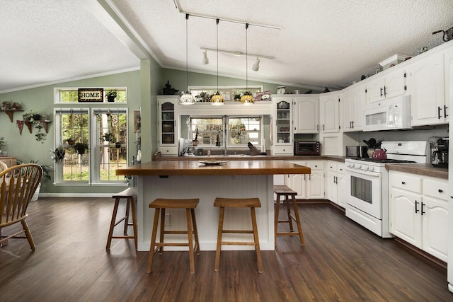 kitchen with a breakfast bar area, a textured ceiling, lofted ceiling, white appliances, and white cabinetry