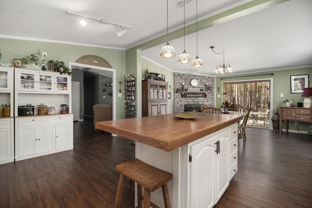 kitchen featuring ornamental molding, a fireplace, dark wood-type flooring, a textured ceiling, and white cabinetry