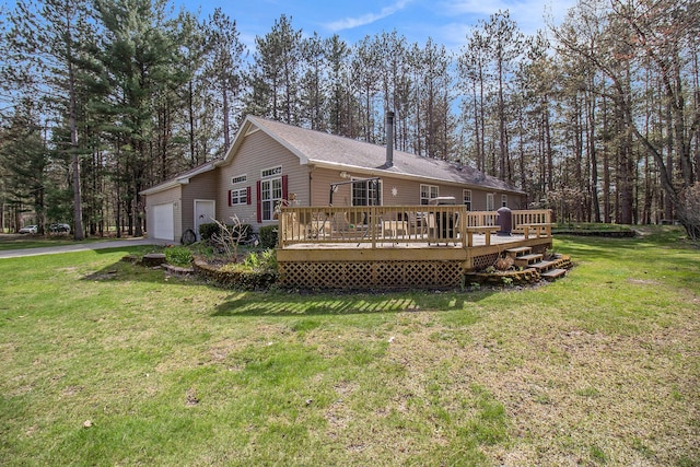 rear view of property with a lawn, a garage, driveway, and a deck