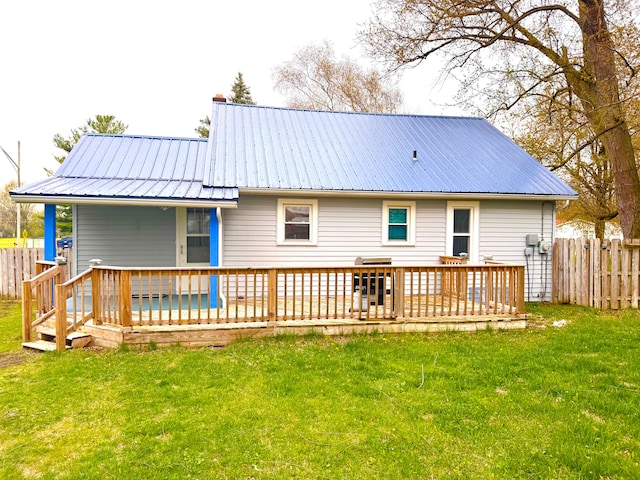 rear view of house with fence private yard, a lawn, and metal roof