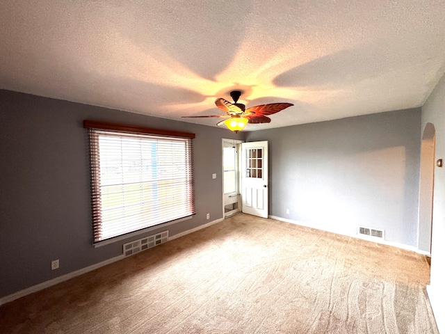 unfurnished room featuring a textured ceiling, ceiling fan, visible vents, and carpet