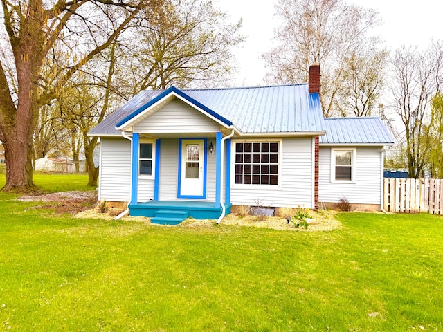 rear view of house with a yard, covered porch, a chimney, and fence