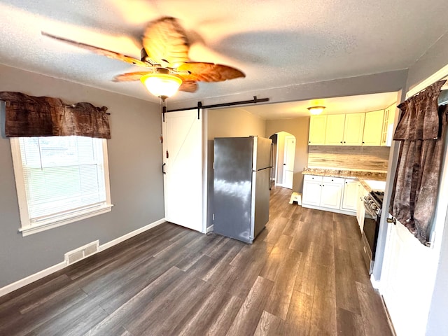 kitchen with visible vents, dark wood-type flooring, a barn door, arched walkways, and stainless steel appliances