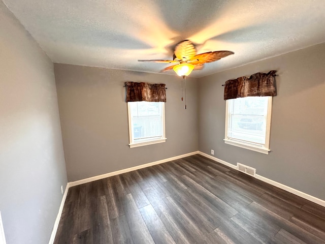 spare room featuring a ceiling fan, a textured ceiling, visible vents, and dark wood-style floors