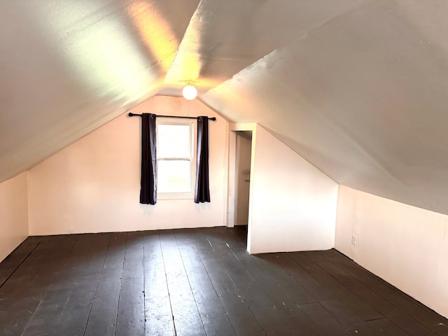additional living space featuring dark wood-style flooring and lofted ceiling