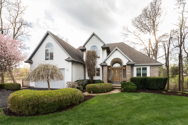 view of front of home featuring brick siding, a garage, a front lawn, and a shingled roof