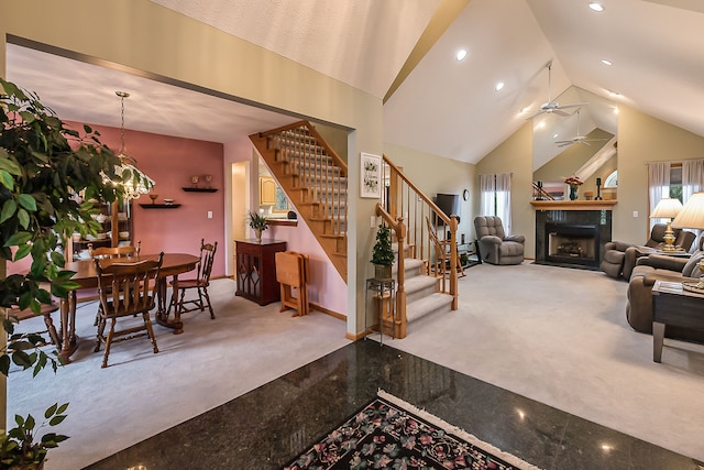 interior space featuring high vaulted ceiling, carpet, stairs, a ceiling fan, and a fireplace with flush hearth