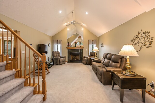 living room with stairway, carpet floors, a fireplace, and a ceiling fan