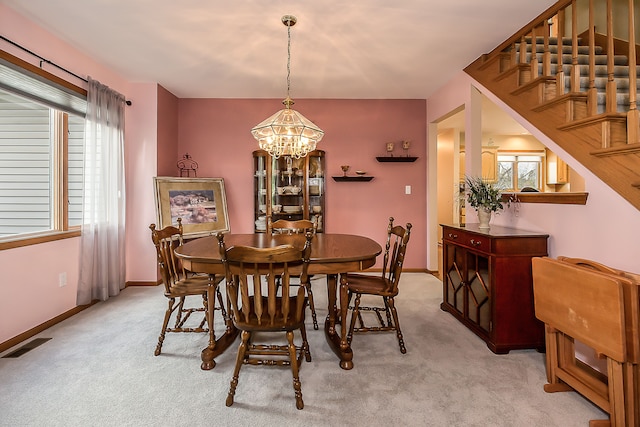 dining room featuring visible vents, light carpet, baseboards, stairway, and a chandelier