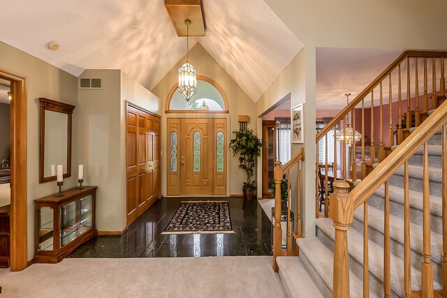 foyer entrance with a notable chandelier, high vaulted ceiling, stairs, baseboards, and visible vents