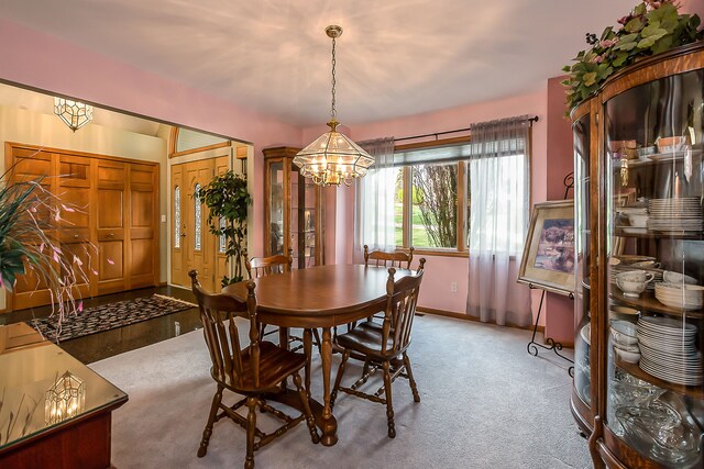 carpeted dining room with an inviting chandelier and baseboards