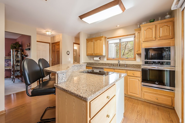 kitchen featuring light brown cabinets, oven, a center island, built in microwave, and a sink