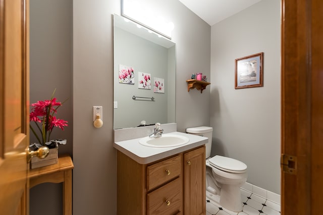 half bathroom featuring vanity, baseboards, and toilet