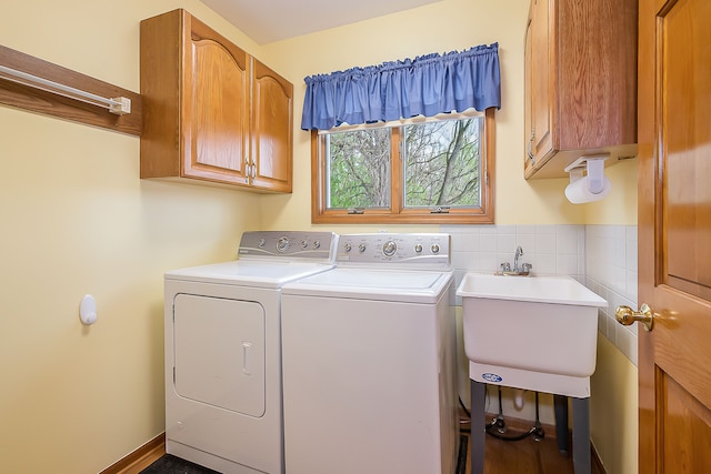 clothes washing area featuring cabinet space, a sink, and washing machine and clothes dryer