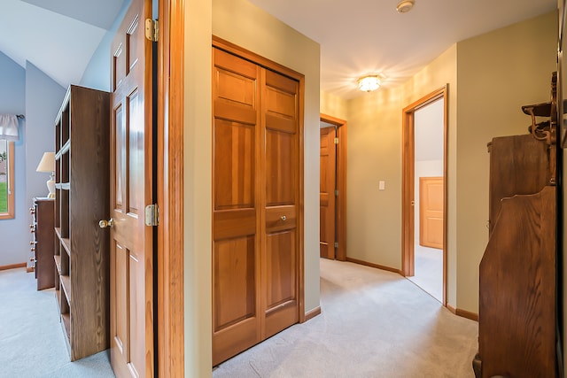 hallway featuring light colored carpet and baseboards