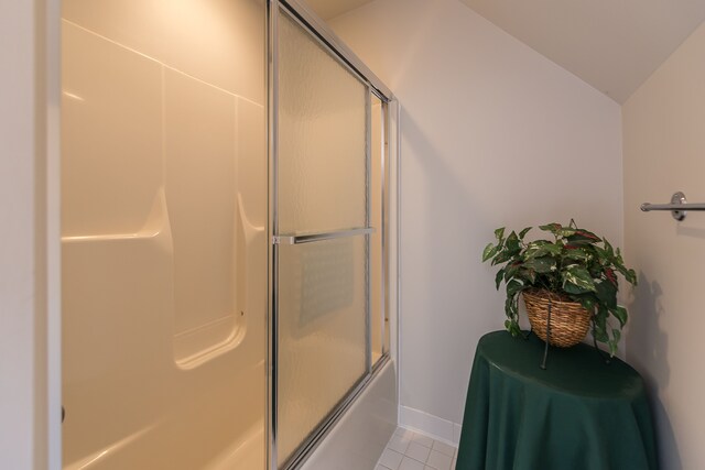 bathroom featuring tile patterned flooring, baseboards, lofted ceiling, and enclosed tub / shower combo