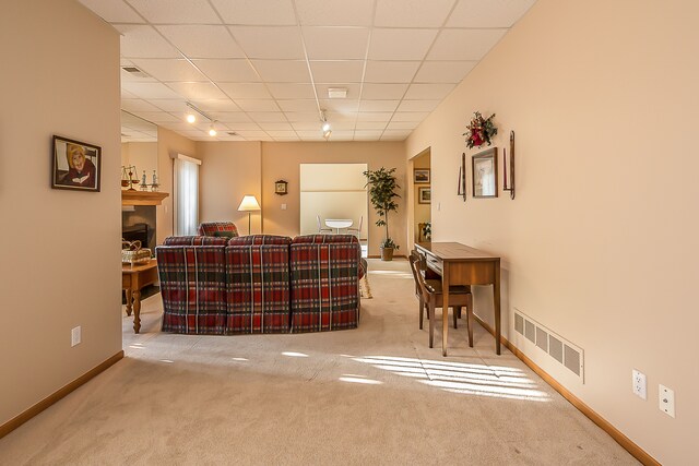 carpeted living room featuring baseboards, visible vents, and track lighting