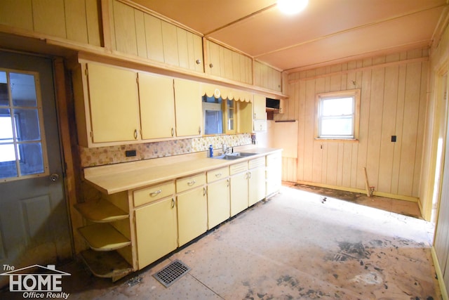 kitchen featuring visible vents, open shelves, light countertops, cream cabinetry, and a sink