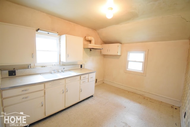 kitchen with lofted ceiling, baseboards, light floors, light countertops, and a sink