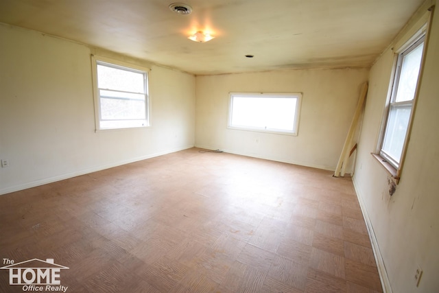 empty room with visible vents, light floors, baseboards, and a wealth of natural light