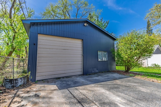 detached garage featuring fence and concrete driveway