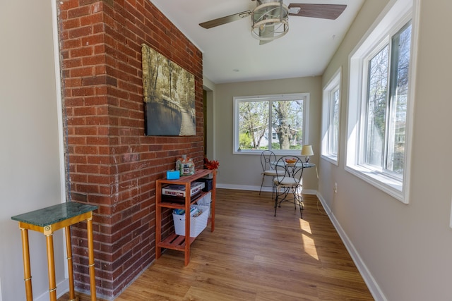 sitting room with a ceiling fan, baseboards, and wood finished floors