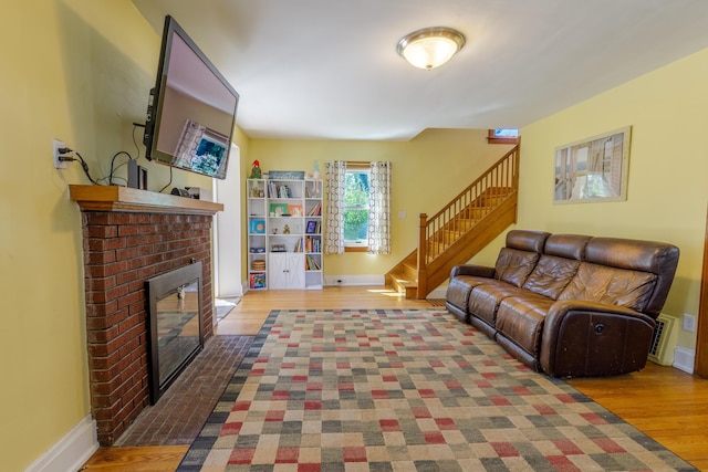 living area featuring visible vents, a fireplace, wood finished floors, baseboards, and stairs