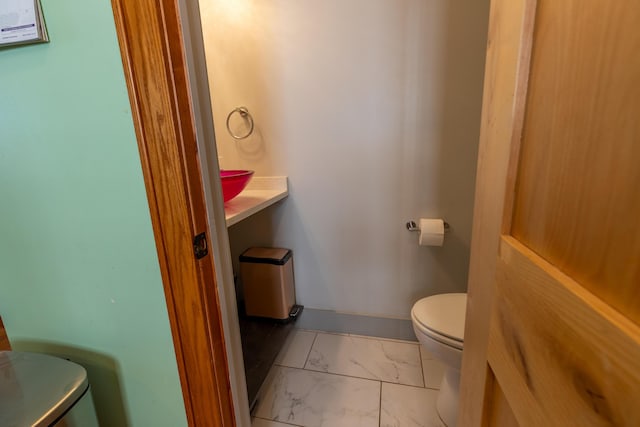 half bathroom featuring toilet and marble finish floor