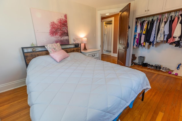 bedroom with a closet, baseboards, and light wood-type flooring
