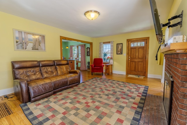 living area featuring baseboards, a fireplace, and wood finished floors