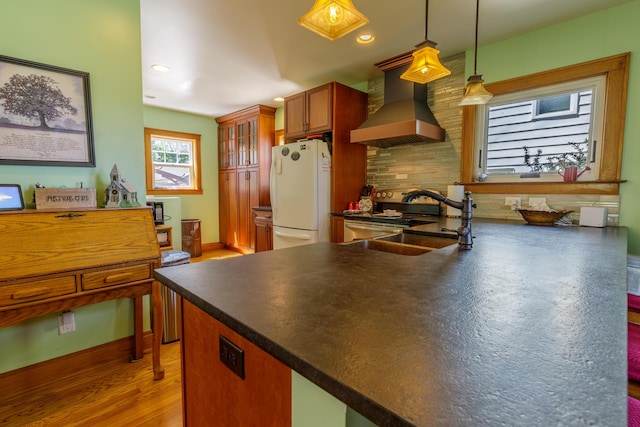 kitchen with freestanding refrigerator, dark countertops, recessed lighting, wall chimney exhaust hood, and backsplash