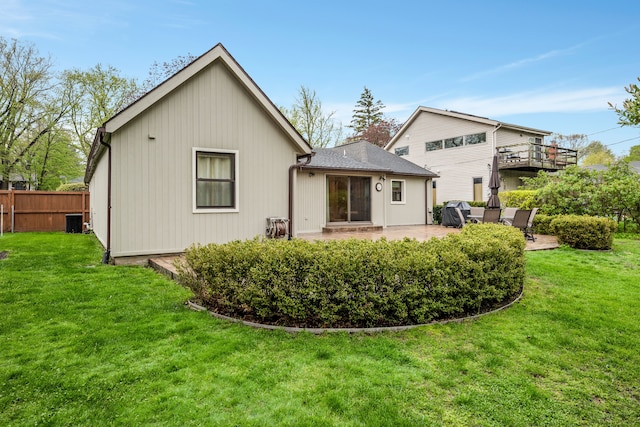 rear view of property featuring a lawn, a patio, fence, and central AC unit