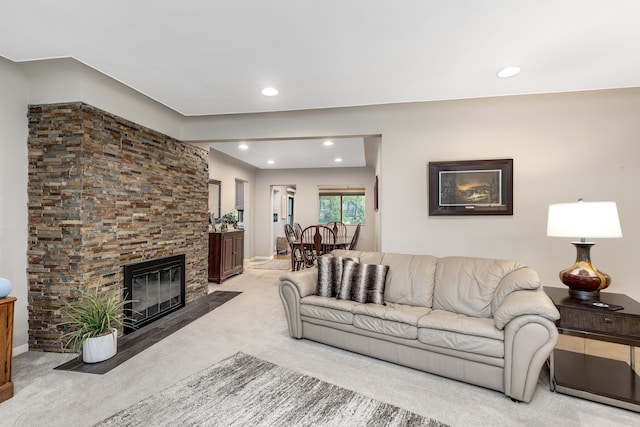 carpeted living area with baseboards, recessed lighting, and a stone fireplace