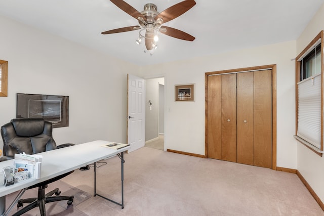 office space with a ceiling fan, baseboards, and light colored carpet