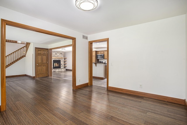 unfurnished room with stairs, baseboards, visible vents, and hardwood / wood-style floors