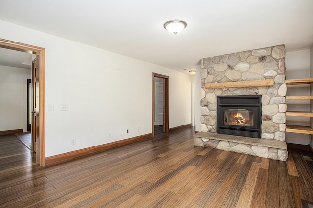 unfurnished living room featuring baseboards, a stone fireplace, and wood finished floors